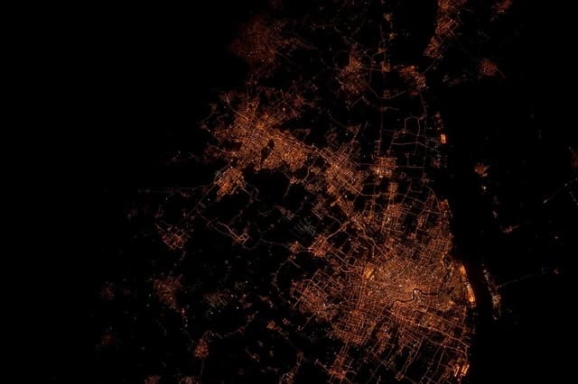 Nighttime satellite view of Shanghai, China, depicting illuminated city streets and buildings.