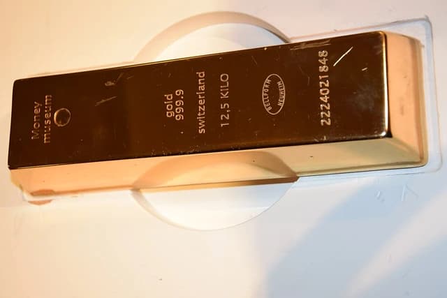 A gold bullion bar with markings for 'gold 999.9 Switzerland 12,5 KILO' on display.