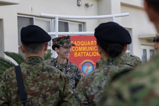 Female Marine officer smiling while speaking with Japan Ground Self-Defense Force personnel.
