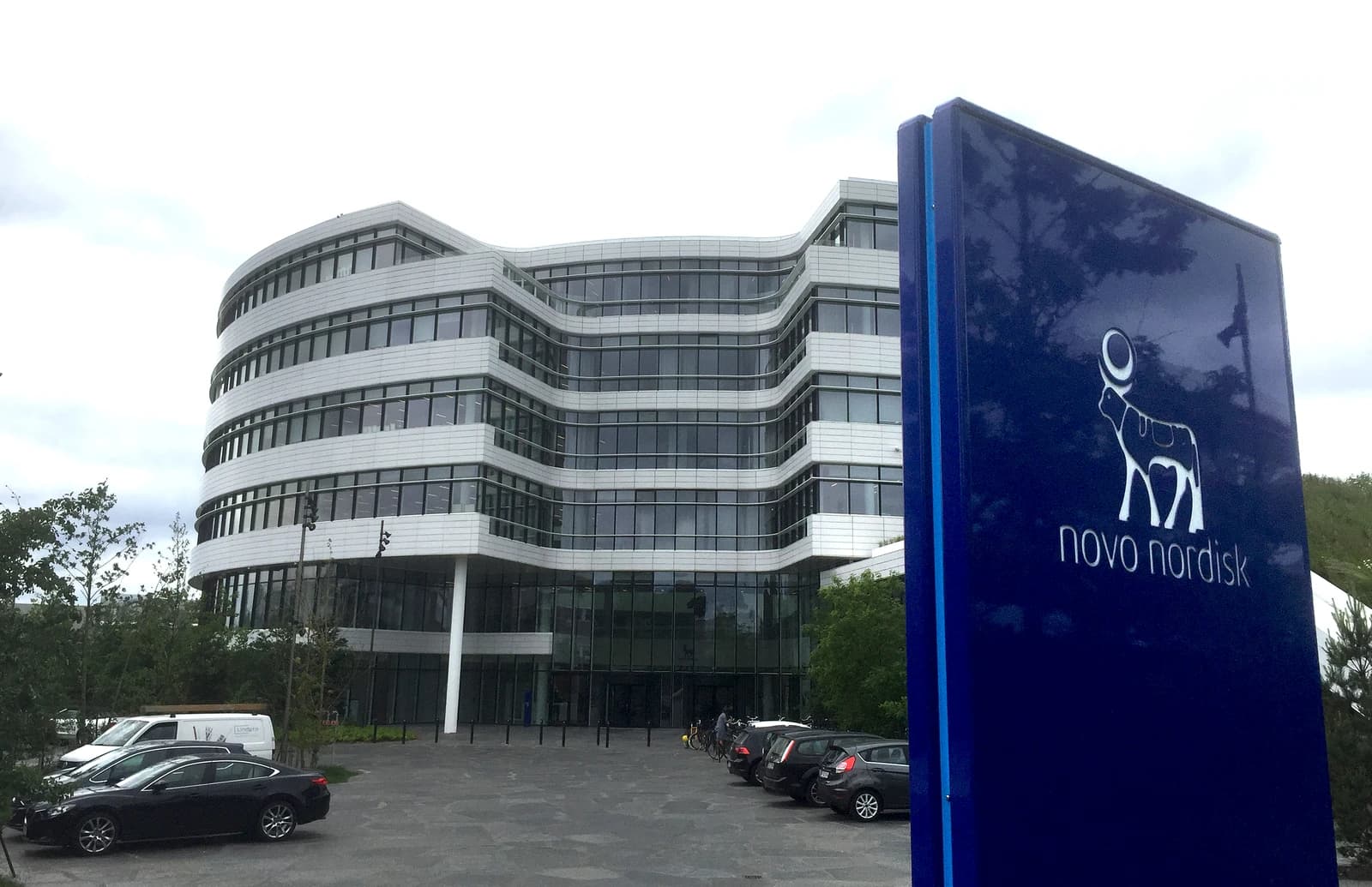 Novo Nordisk headquarters building in Denmark, with blue company sign in foreground.