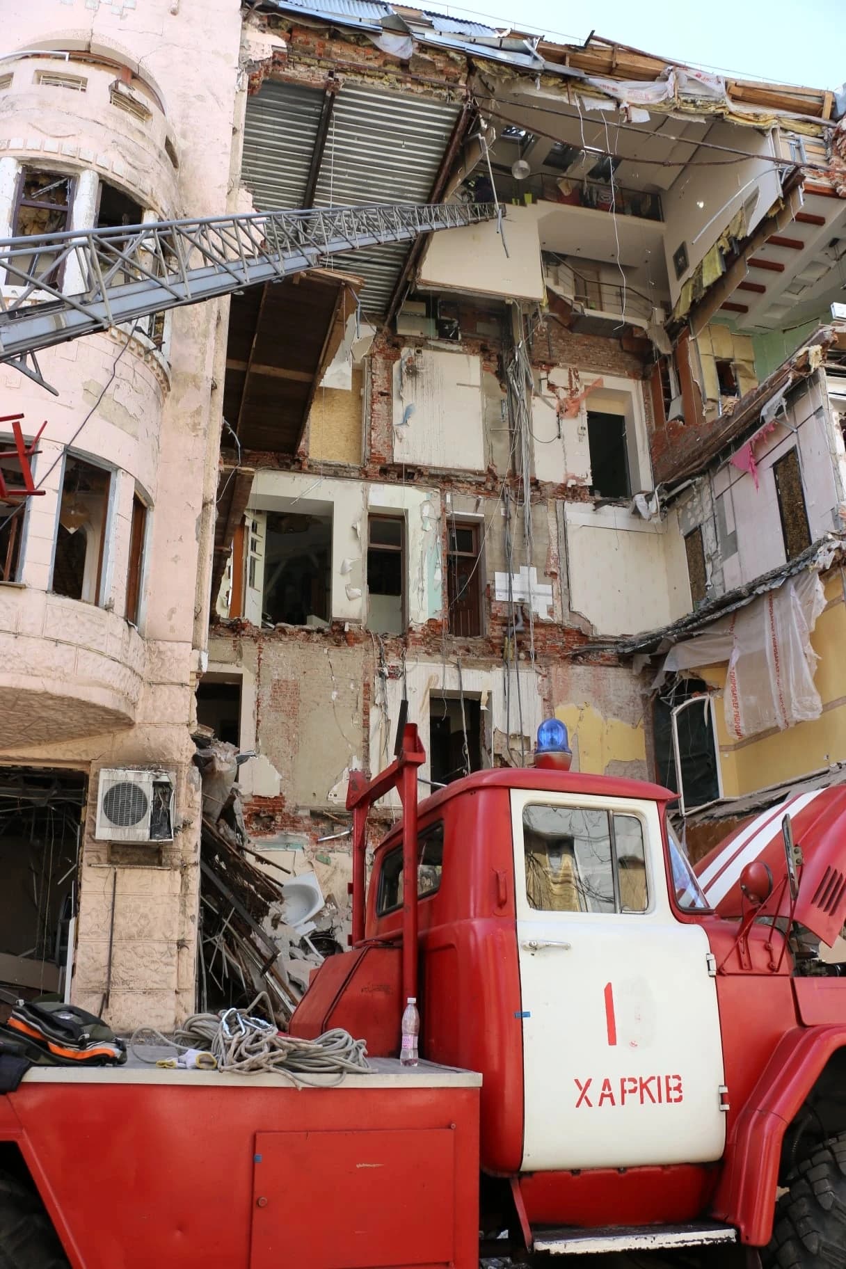 Damaged Maslovsky Revenue House in Kharkiv, Ukraine, with a fire truck in front.