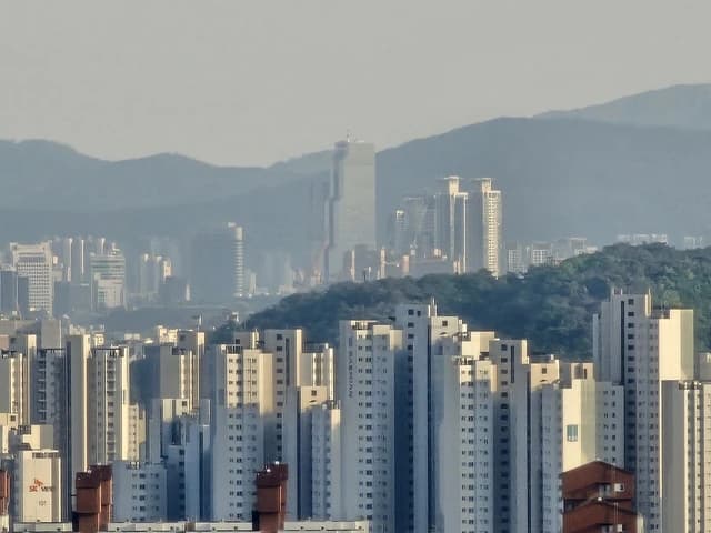 Cityscape of Gangnam-gu, Seoul, showing numerous high-rise buildings and distant mountains.