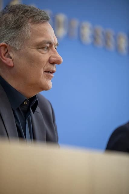 Man with gray hair speaking at the Bundespressekonferenz, a press conference.