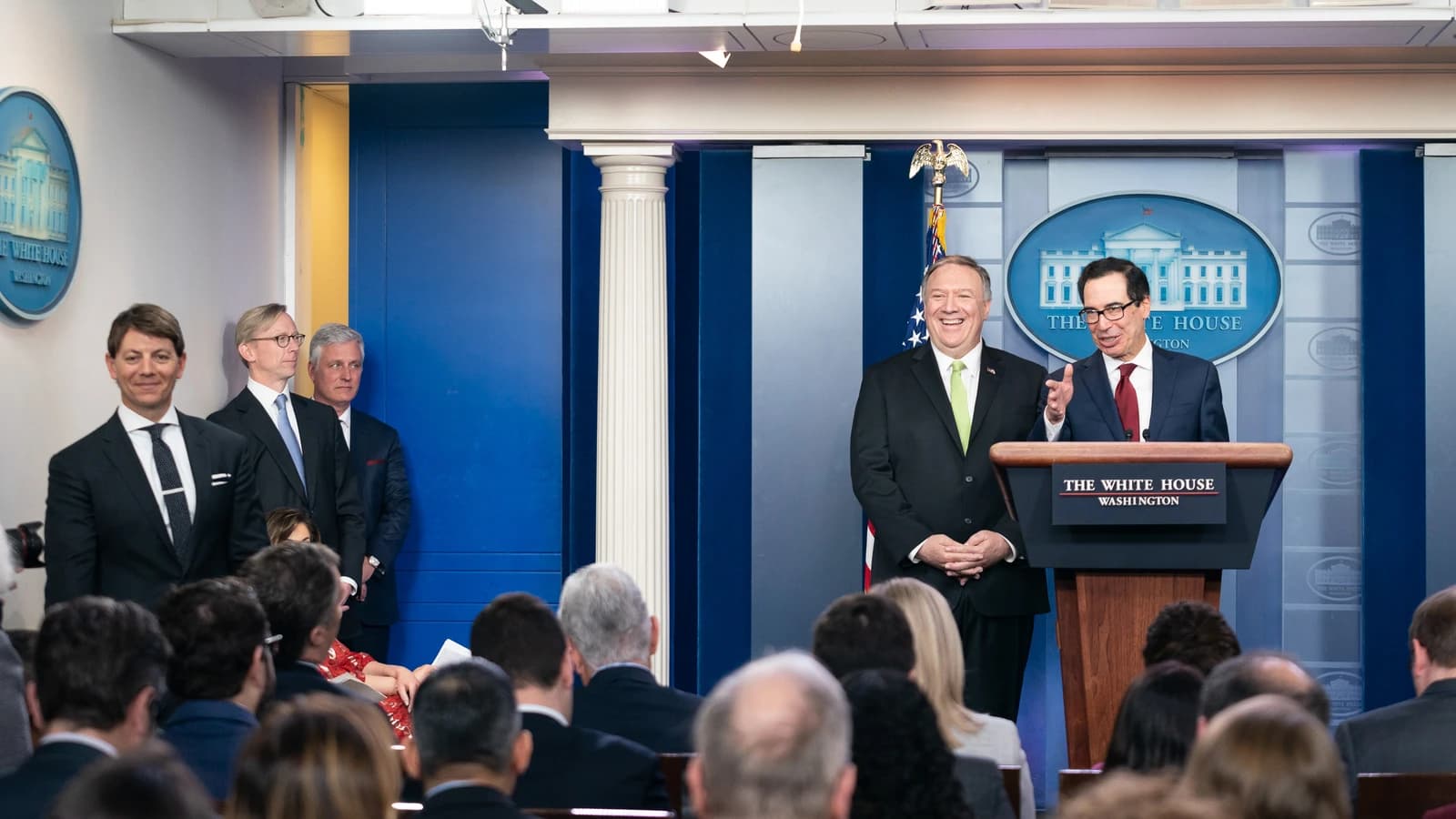 Steven Mnuchin, Secretary of the Treasury, speaks at a podium next to Mike Pompeo.