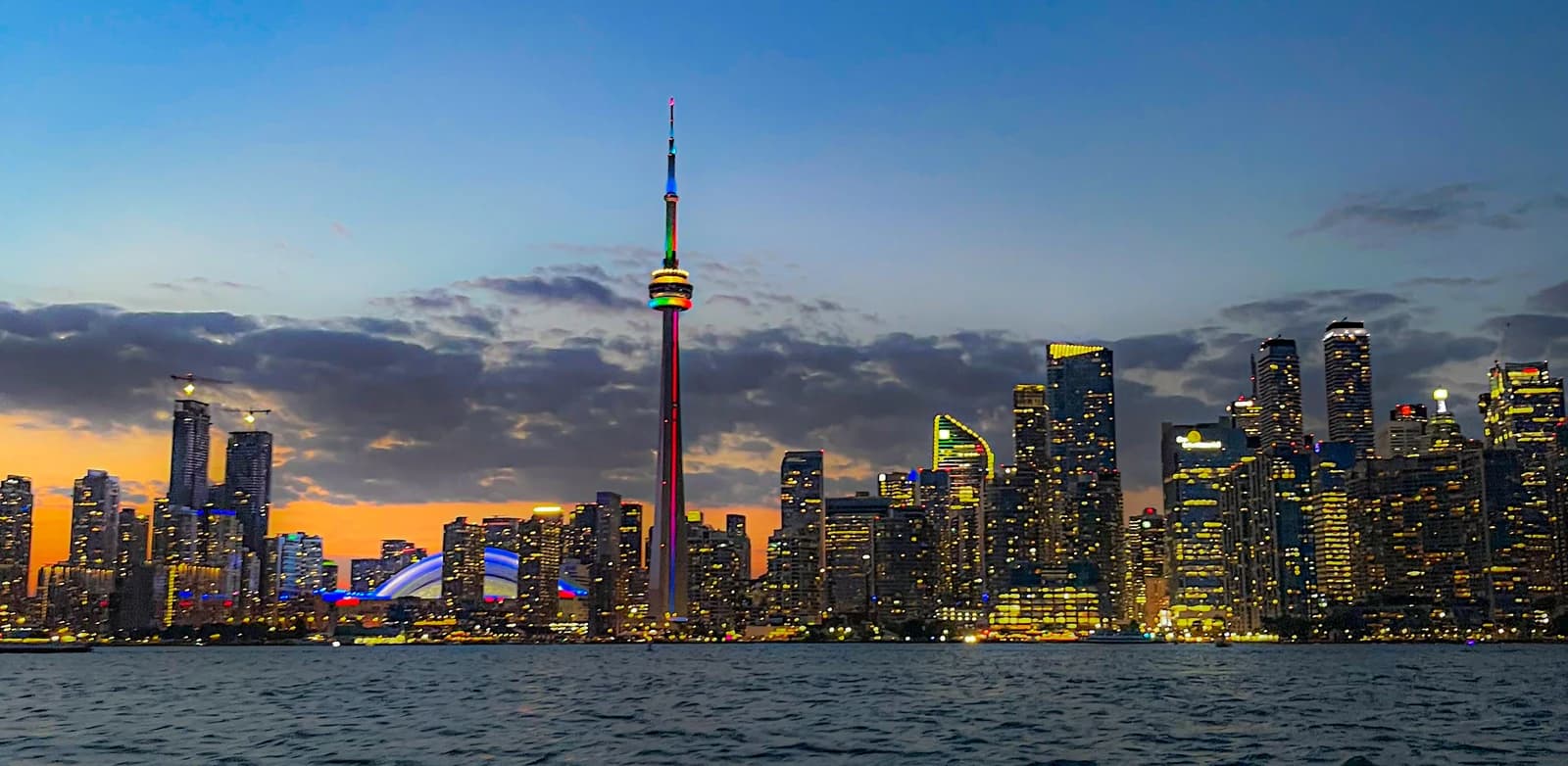 Toronto skyline at night, with the illuminated CN Tower prominent among the city's buildings.