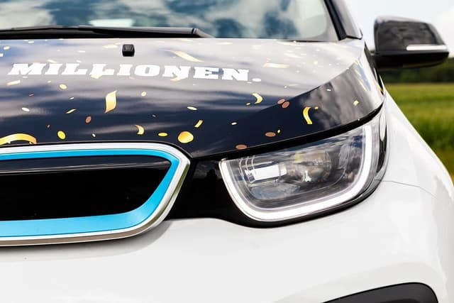 Close-up of the front of a white BMW i3 electric car with confetti graphics.
