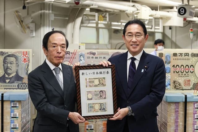 Prime Minister Fumio Kishida and Governor Kazuo Ueda holding a framed display of Japanese banknotes.