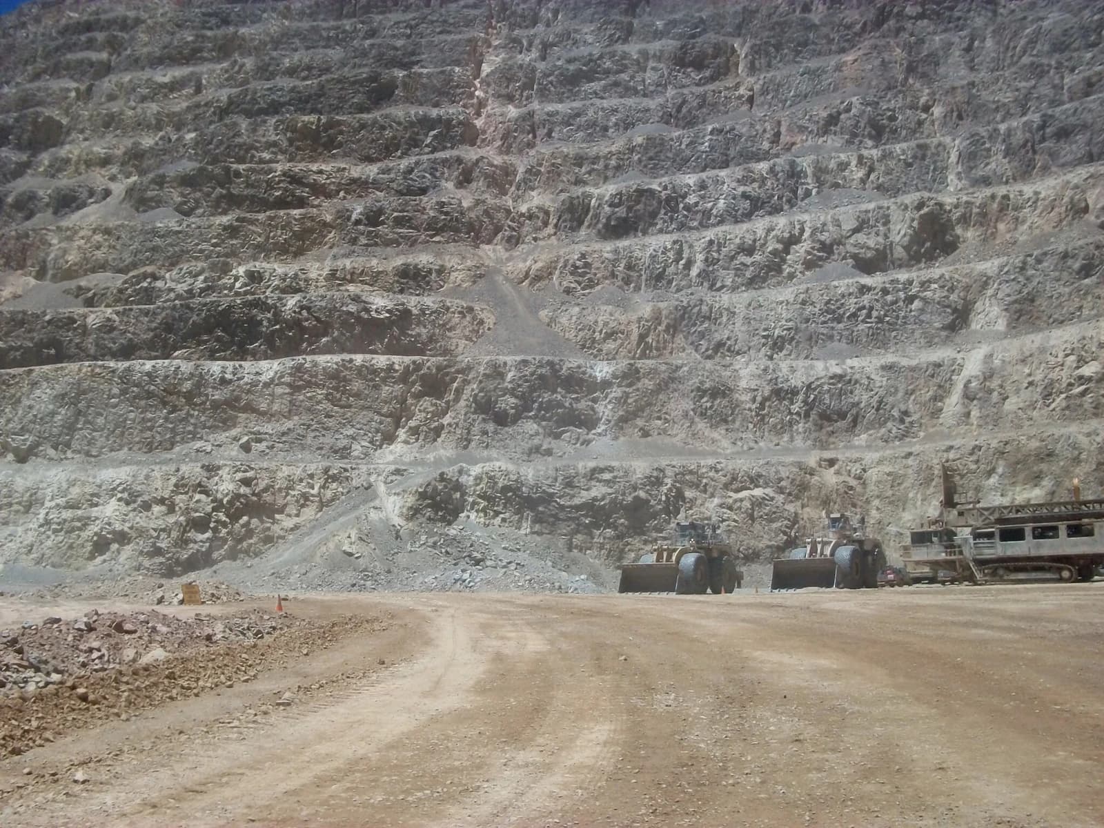 Heavy mining equipment parked at the base of a large open-pit mine.