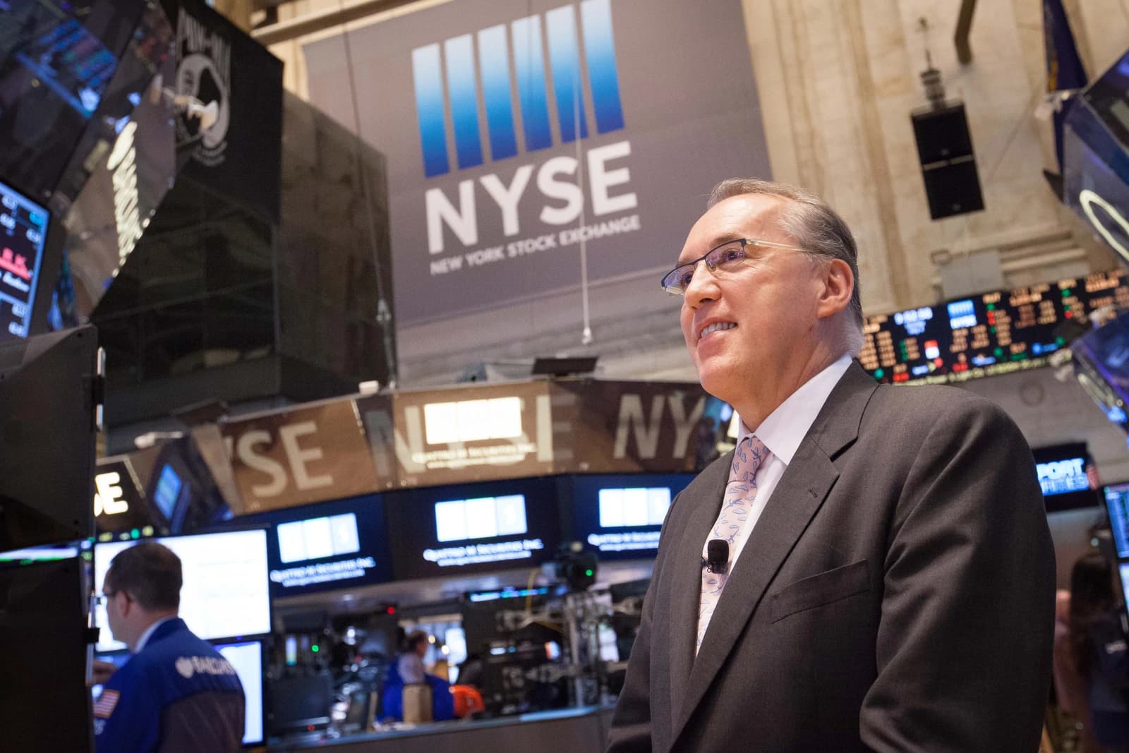 Frank Holmes standing in front of a large NYSE sign at the New York Stock Exchange.