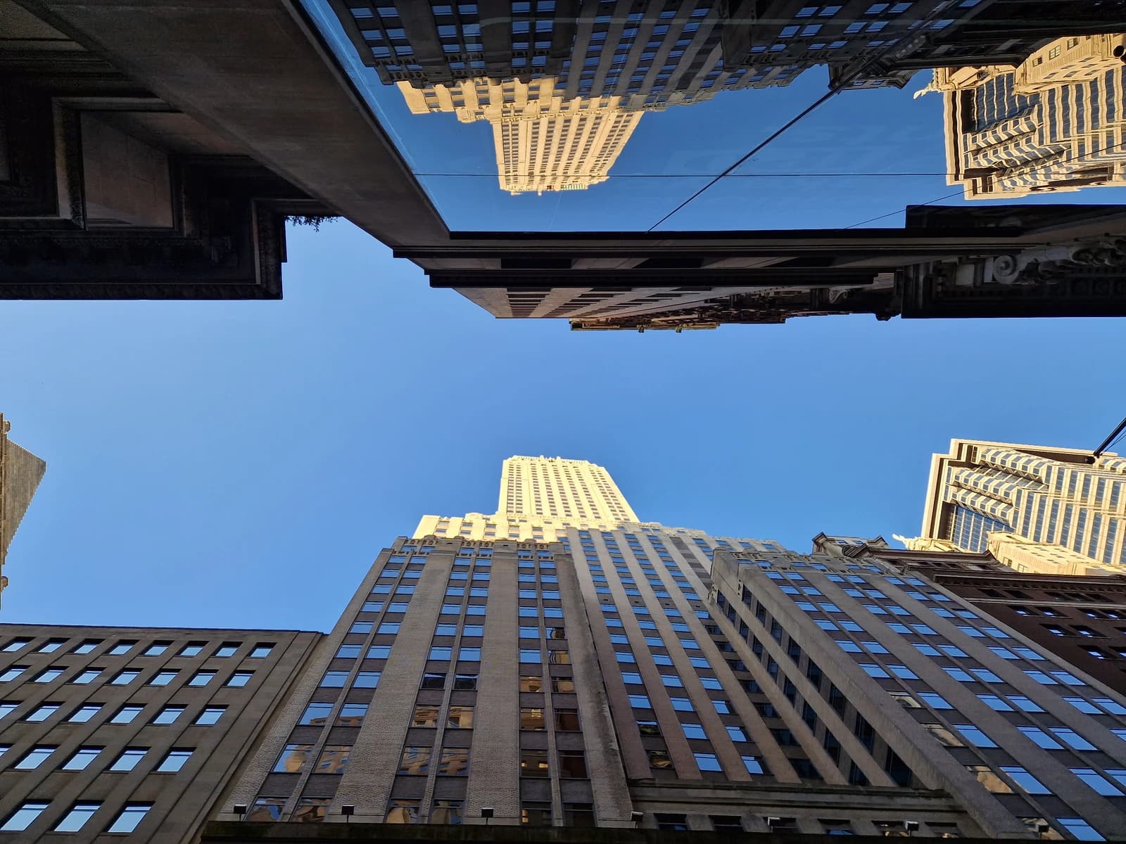 Skyscrapers reflect in a glass overhang on Wall Street, Manhattan, New York City.