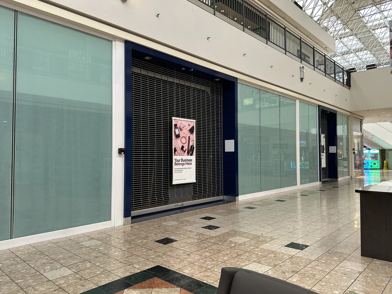 Closed retail storefront with metal security gates inside a shopping mall.
