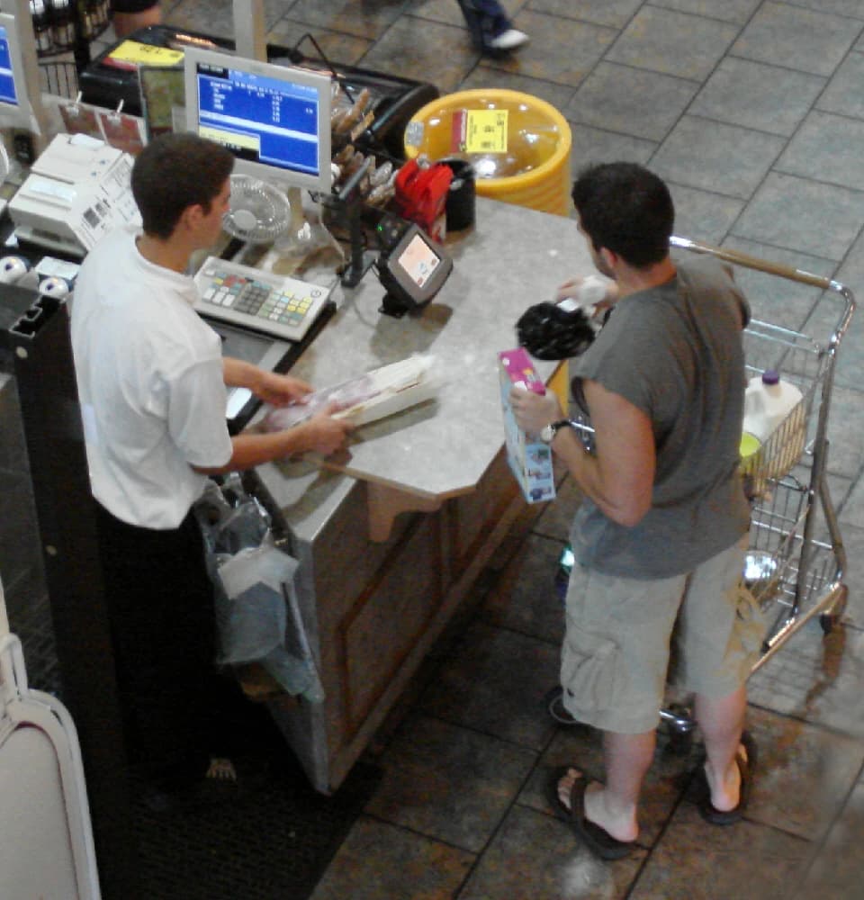 A cashier scanning items for a customer at a grocery store checkout.