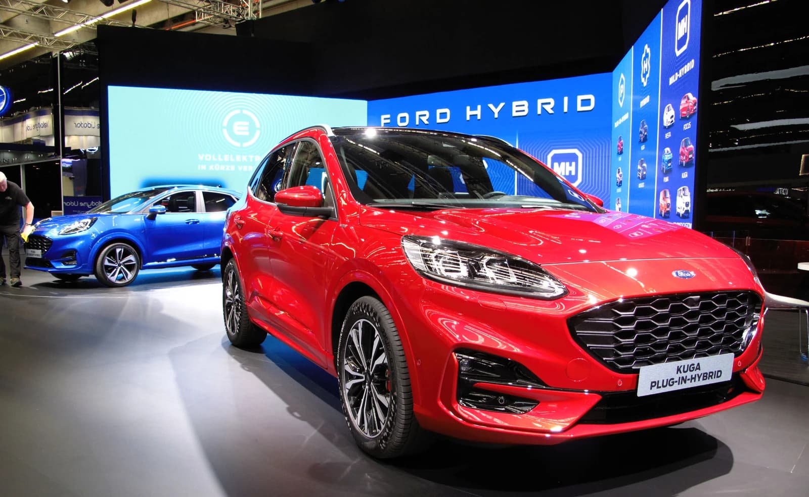 A red Ford Kuga Plug-in Hybrid SUV on display indoors.