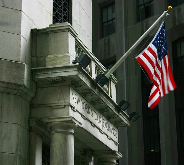 Main entrance of the New York Stock Exchange building with an American flag displayed.