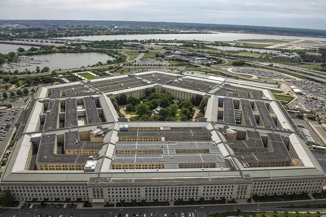 Aerial view of the Pentagon building, its five sides visible, with surrounding roads and river.