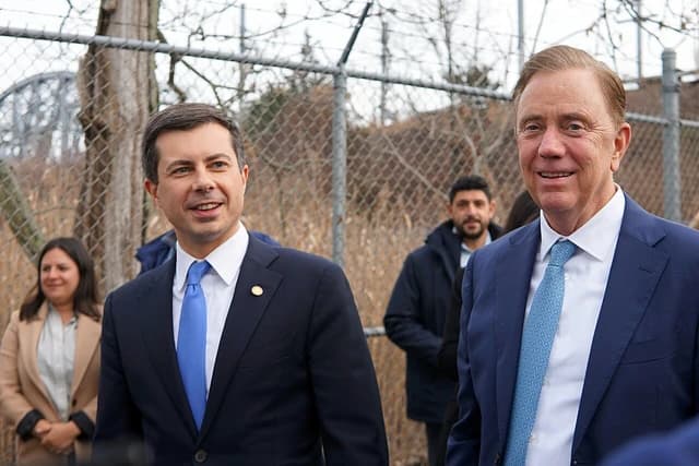 Pete Buttigieg, US Secretary of Transportation, standing outdoors with another official.
