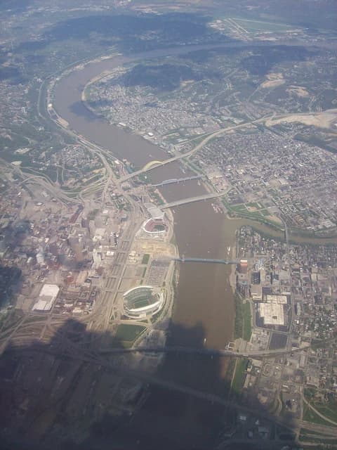 Aerial view of Cincinnati, Ohio, showing river, bridges, and city infrastructure.