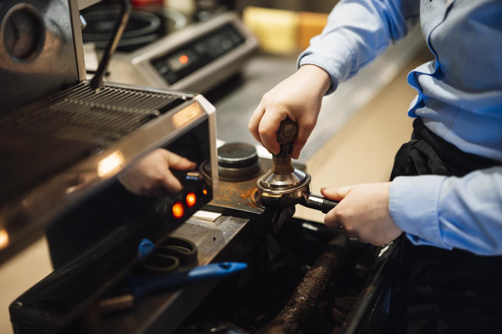 Barista tamping ground coffee into a portafilter using a tamper tool.