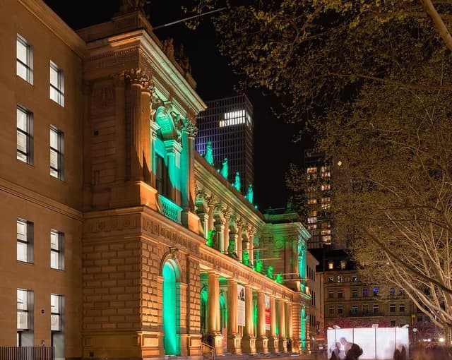 Frankfurt Stock Exchange building illuminated in green lights at night.