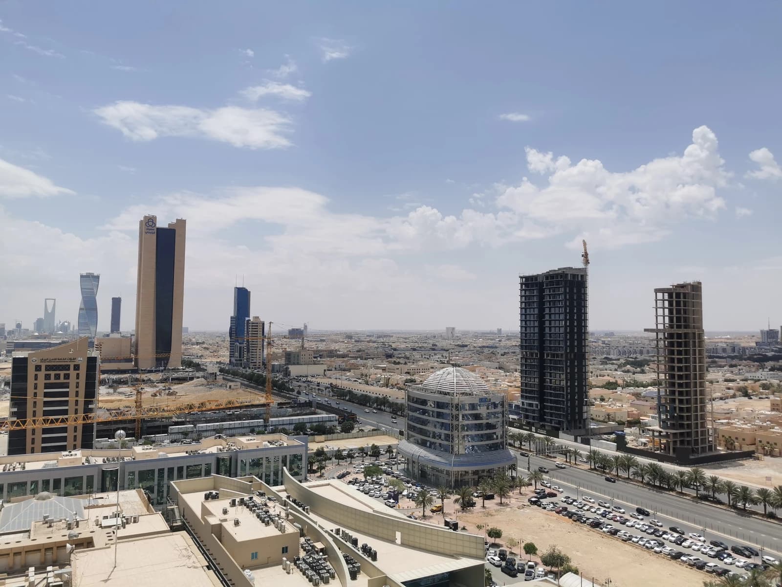 Overview of multiple modern buildings and construction sites in a desert city.