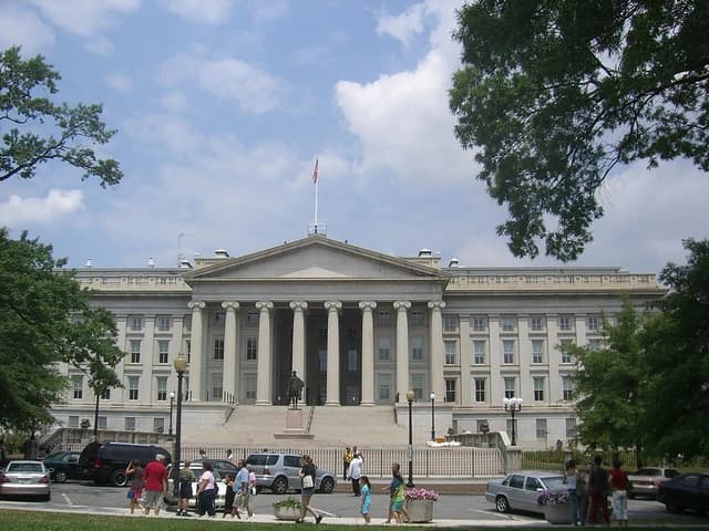 The U.S. Department of the Treasury headquarters in Washington, D.C., under a partly cloudy sky.