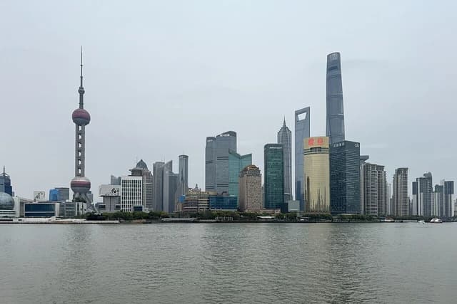 Shanghai skyline showing the Oriental Pearl TV Tower and many tall skyscrapers from across the water.