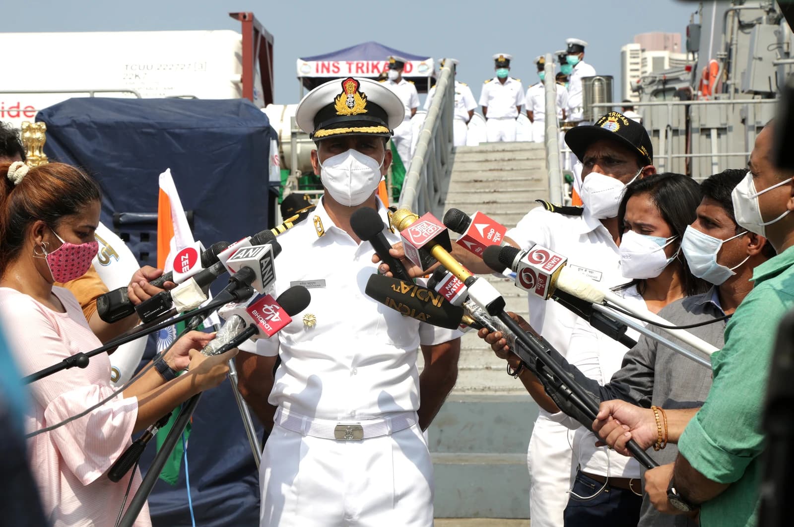 Captain Harish Bahuguna, Commanding Officer of INS Trikand, speaks to reporters with microphones.