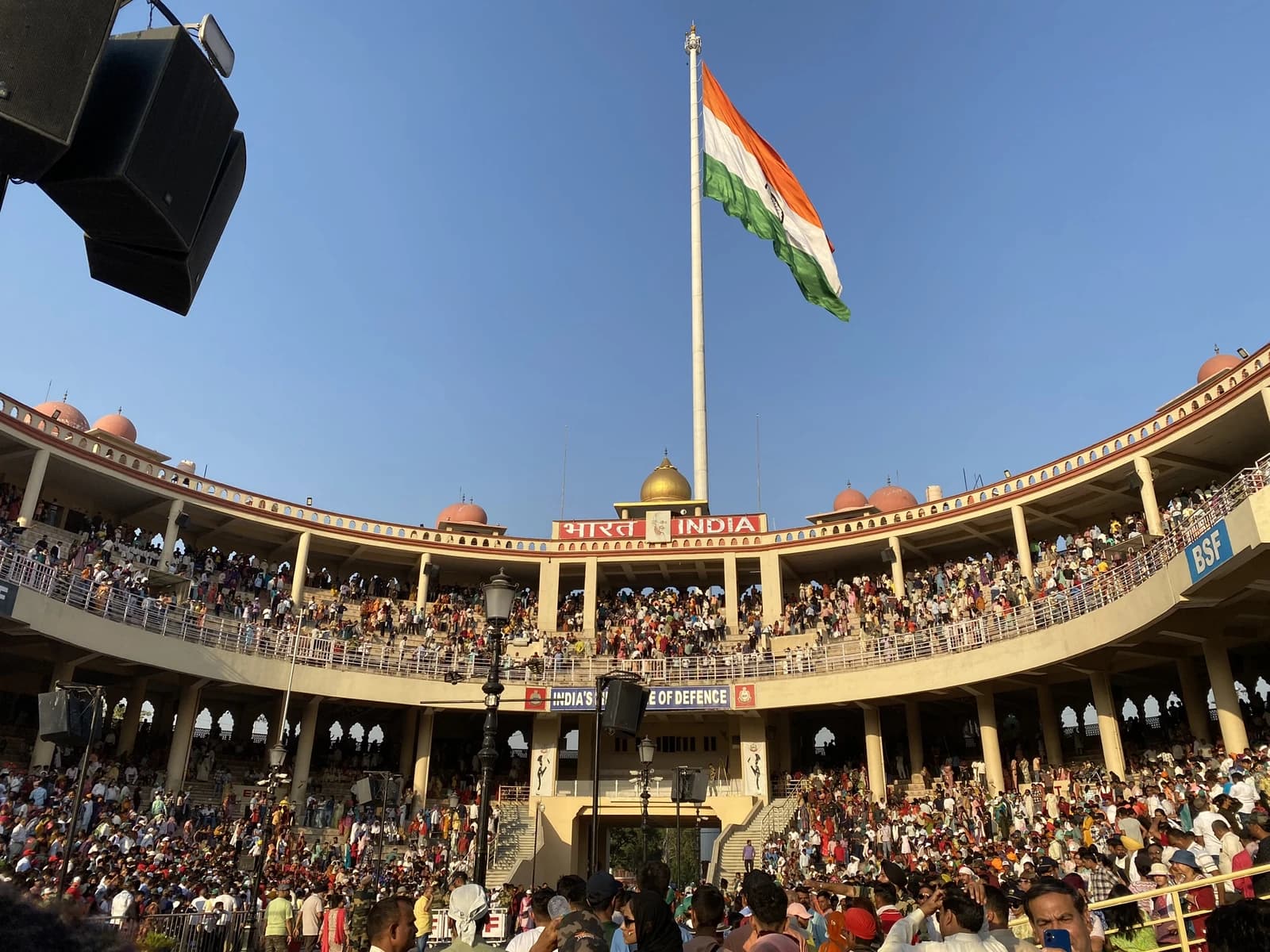 Indian flag flying prominently over the Attari-Wagah border gate with spectators.
