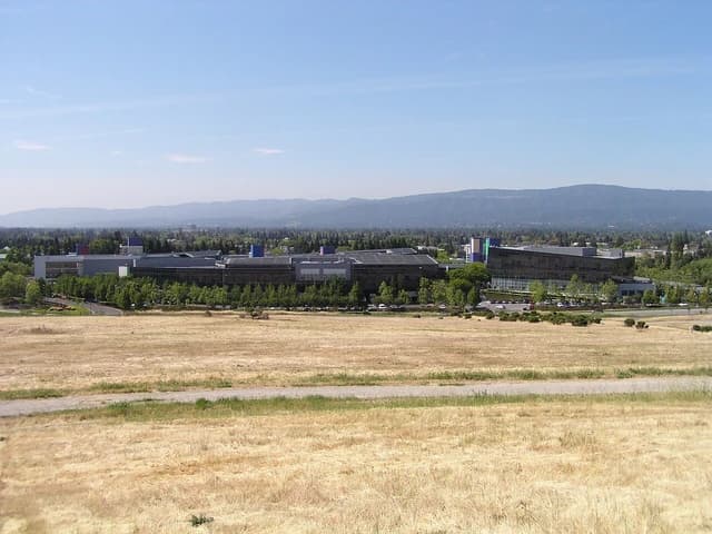 Buildings of Google's headquarters campus in Mountain View, California under a clear sky.
