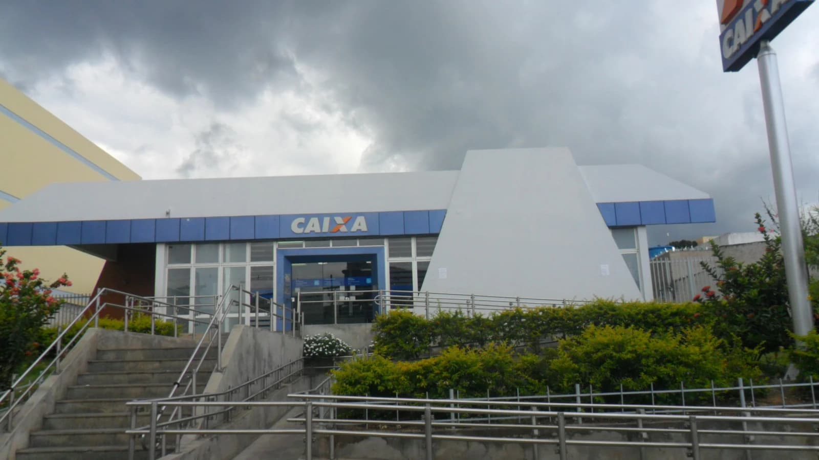 Exterior view of a Caixa bank branch building under a cloudy sky.