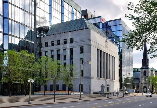 Exterior view of the Bank of Canada building in Ottawa, Ontario, with surrounding trees and street.