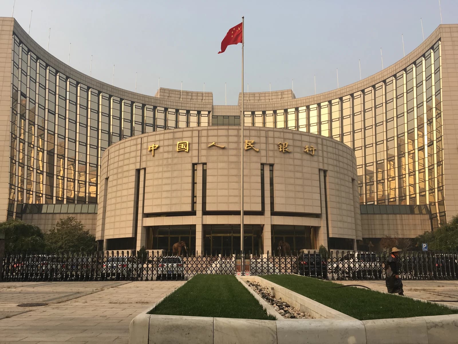 The People's Bank of China headquarters building in Beijing, with a Chinese flag flying.