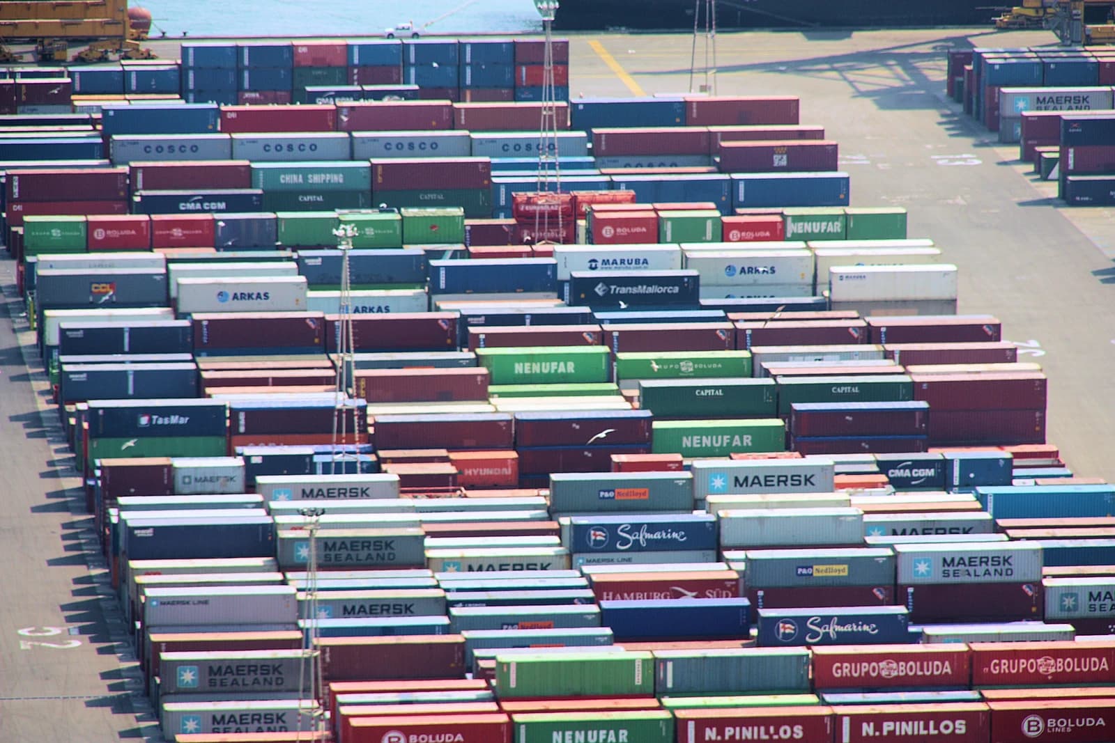Shipping containers from Maersk, Nenufar, Arkas, and Cosco stacked at Port of Barcelona.