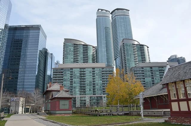 Tall glass skyscrapers towering over smaller historic red buildings and railway tracks.