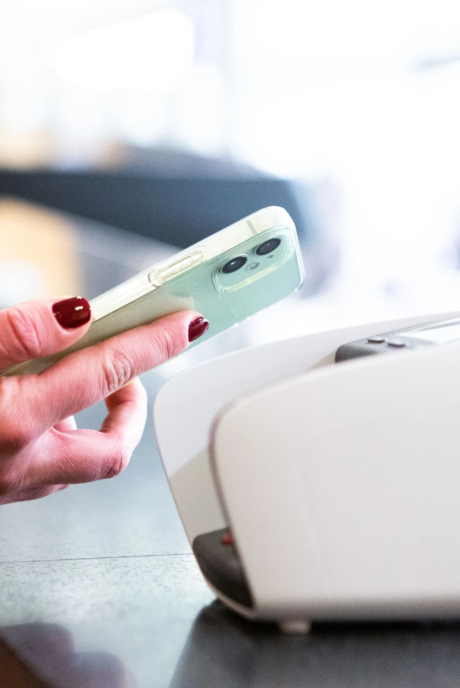 A person holds a smartphone over a payment terminal to make a transaction.