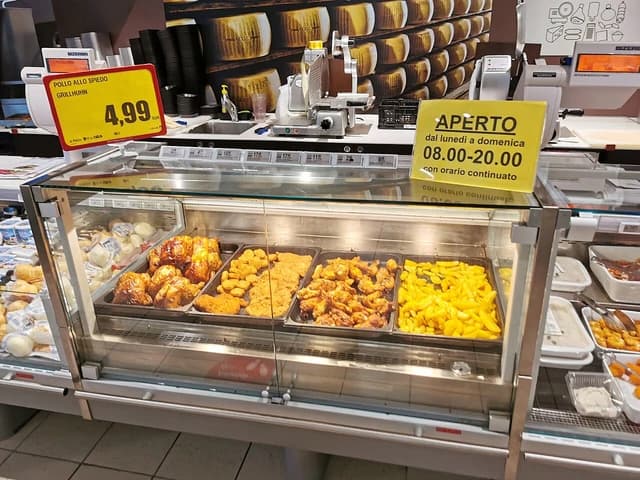 Cooked chicken and other prepared foods in a supermarket display case.