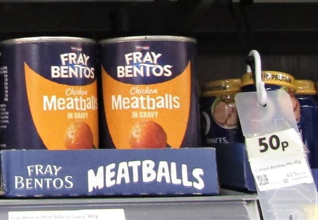 Fray Bentos chicken meatballs in gravy cans displayed on a supermarket shelf.
