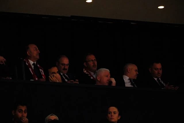 Mevlüt Çavuşoğlu, Turkish politician, looks up while attending an event with other individuals.