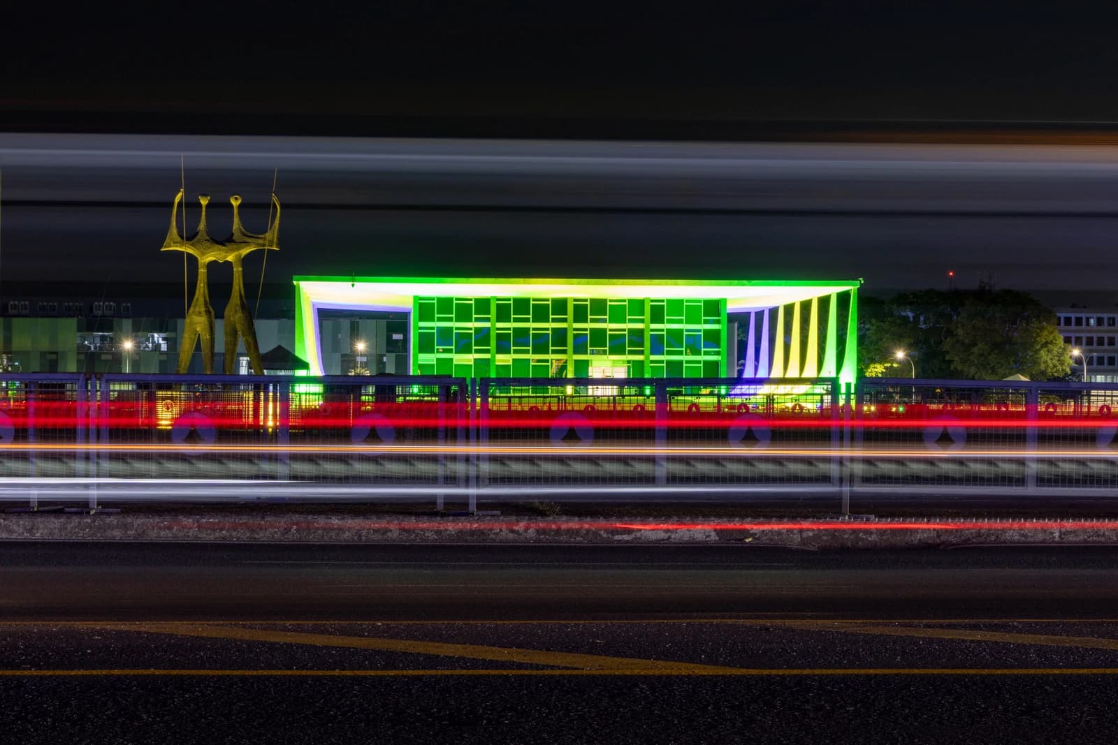 Exterior of the Supremo Tribunal Federal building in Brazil at night, illuminated green and yellow.
