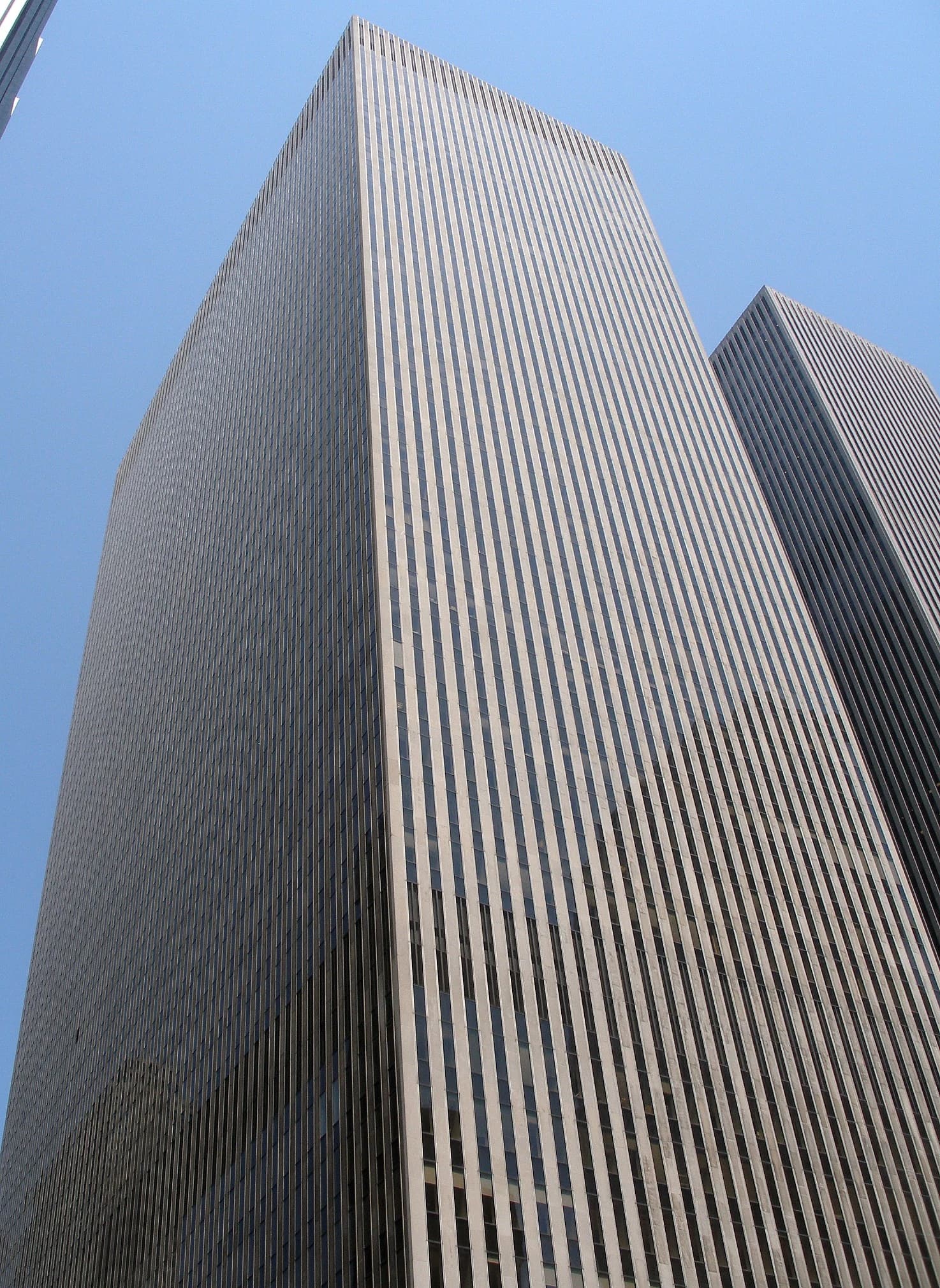 Tall corporate buildings with vertical striped facades against a clear blue sky.