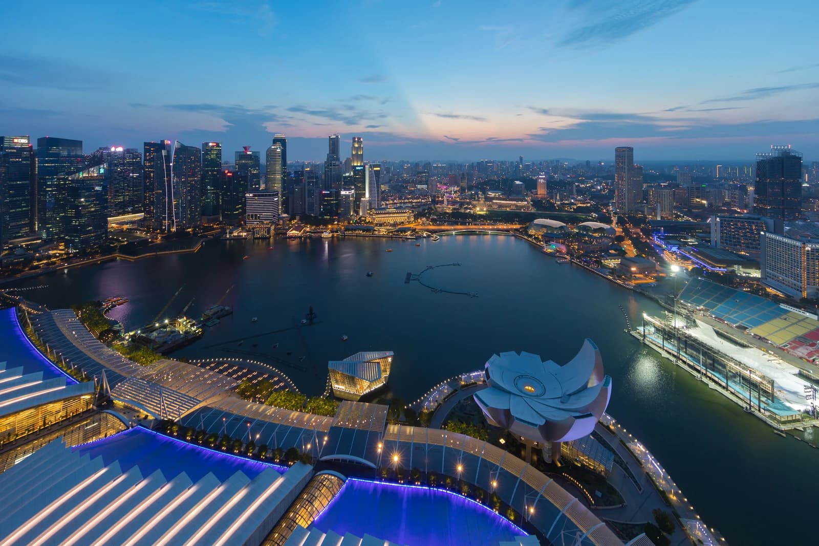 Singapore's Central Business District skyline at dusk with lights reflecting on Marina Bay.
