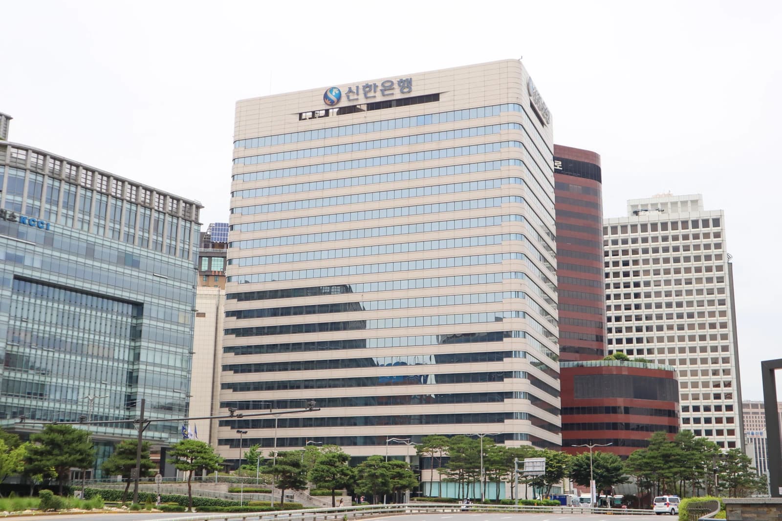 Exterior of Shinhan Bank headquarters building, a tall light-colored building with many windows.