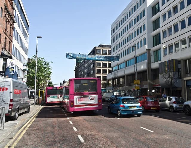 A street in Belfast, Northern Ireland, with several buses and cars driving on the road.
