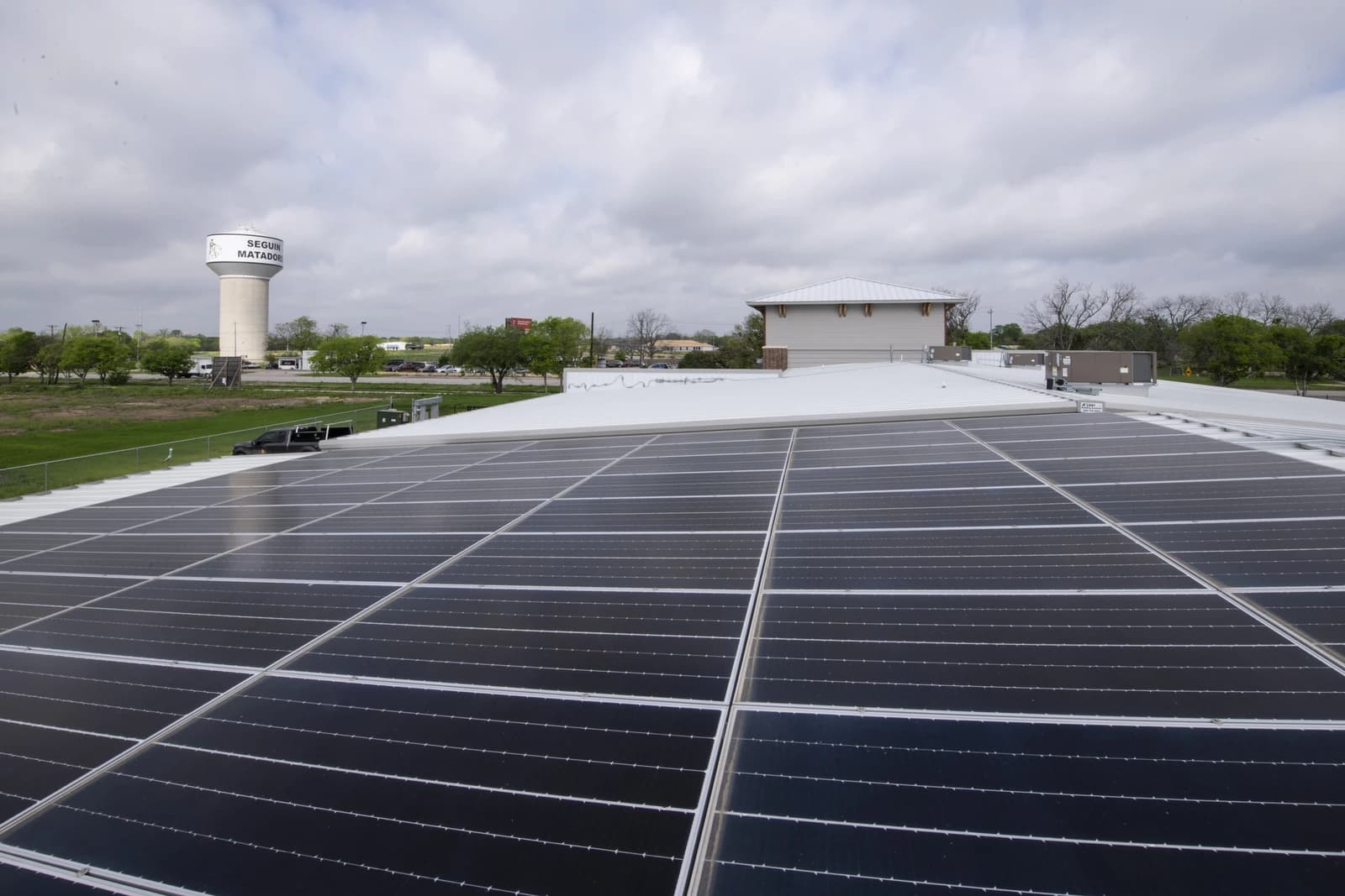 Solar panels installed on a white roof with a distant water tower.