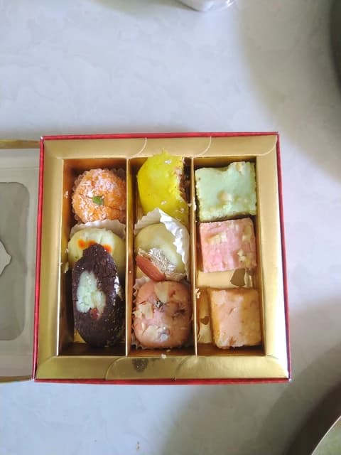 An open box containing an assortment of traditional Indian sweets.