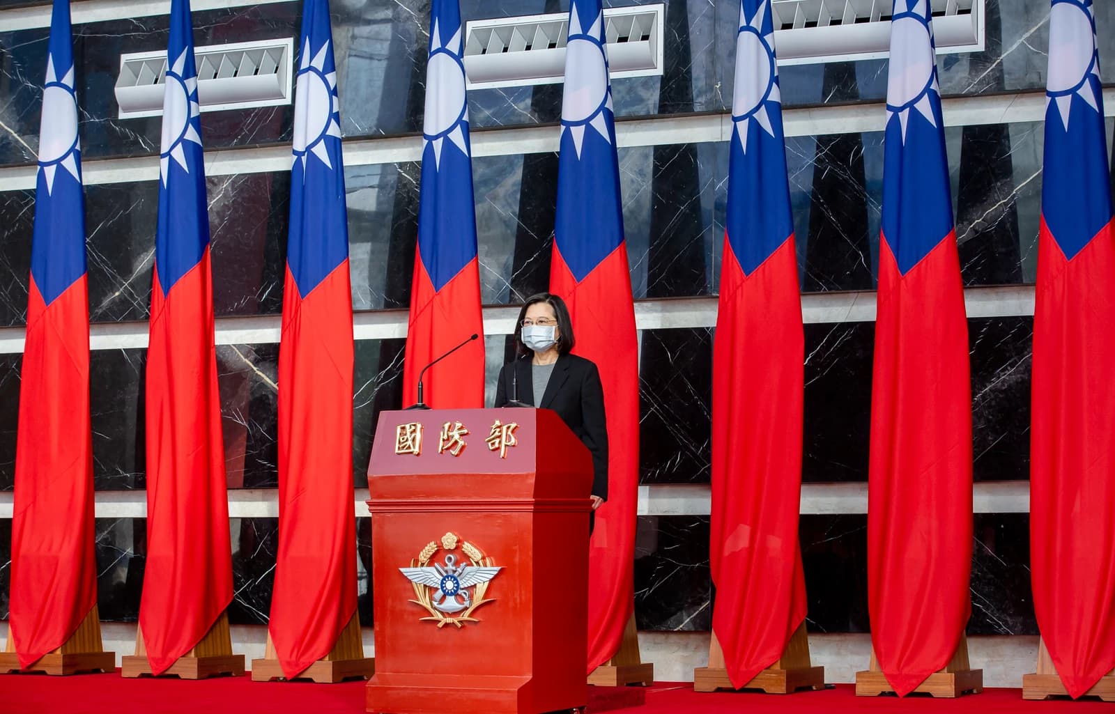 Taiwanese President Tsai Ing-wen stands at a podium in front of Taiwanese flags.
