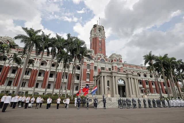 Military personnel stand in formation on a parade ground in front of the Taiwan Presidential Building.