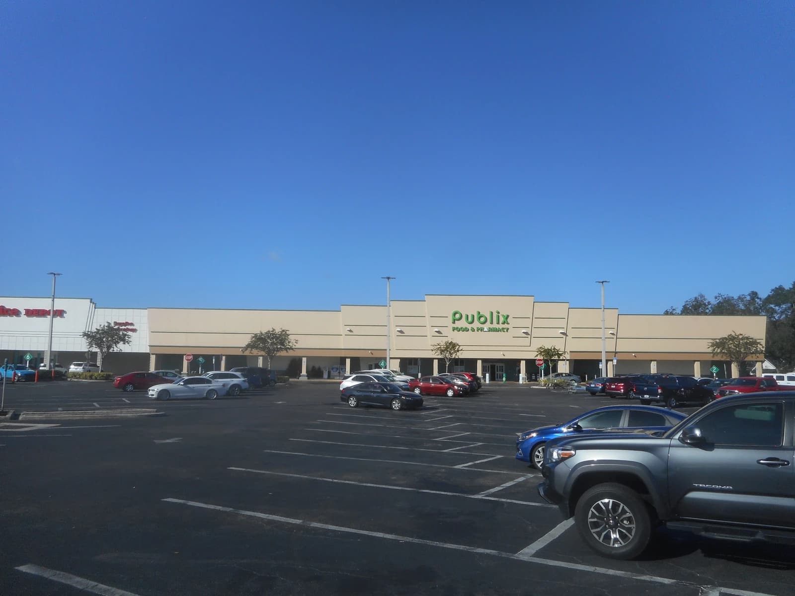 Exterior of Publix grocery store with parking lot and other retail buildings.
