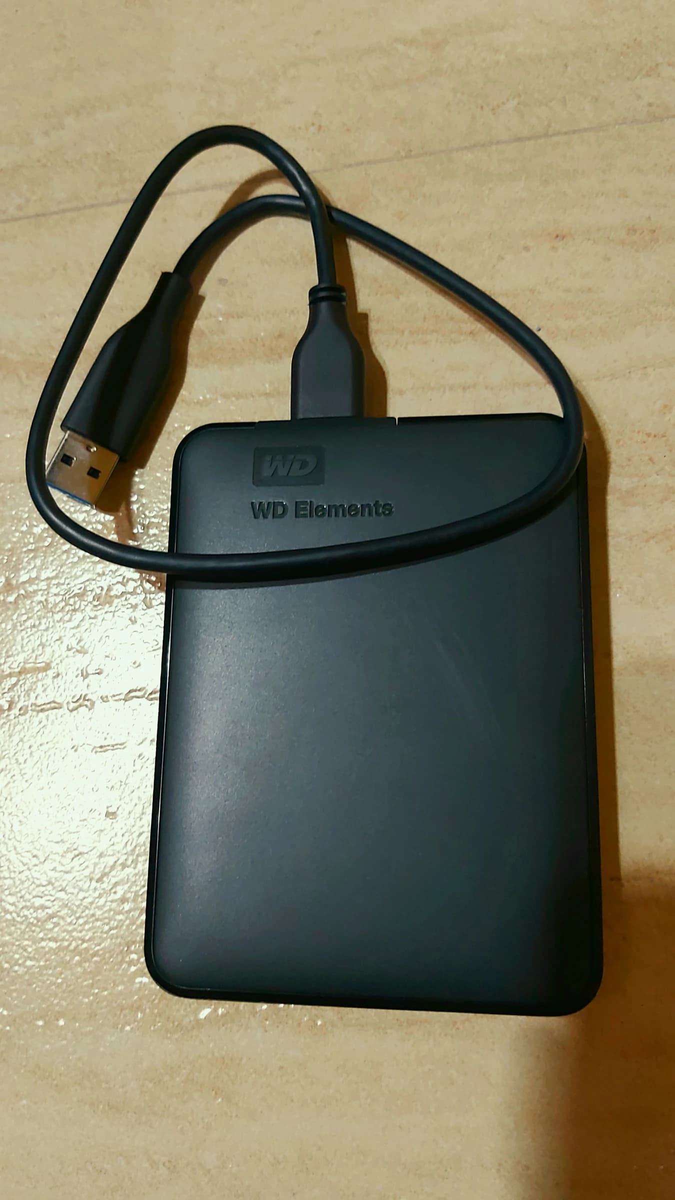 A black Western Digital Elements external hard drive connected to a black USB cable.