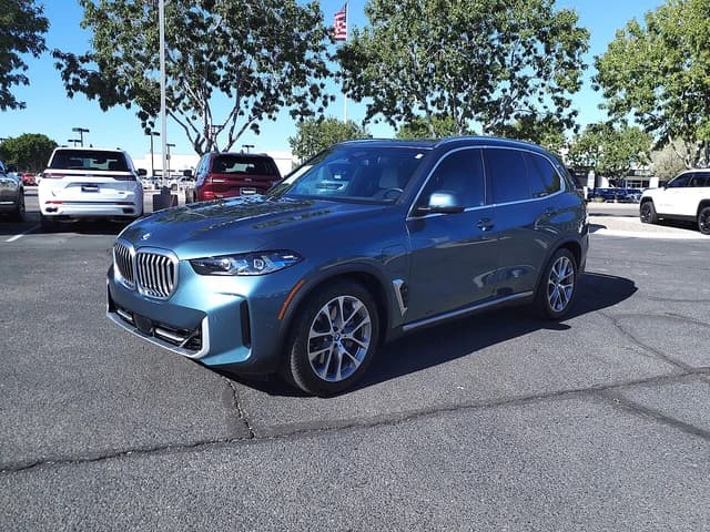 Blue 2024 BMW X5 xDrive50e PHEV SUV parked in an outdoor lot.